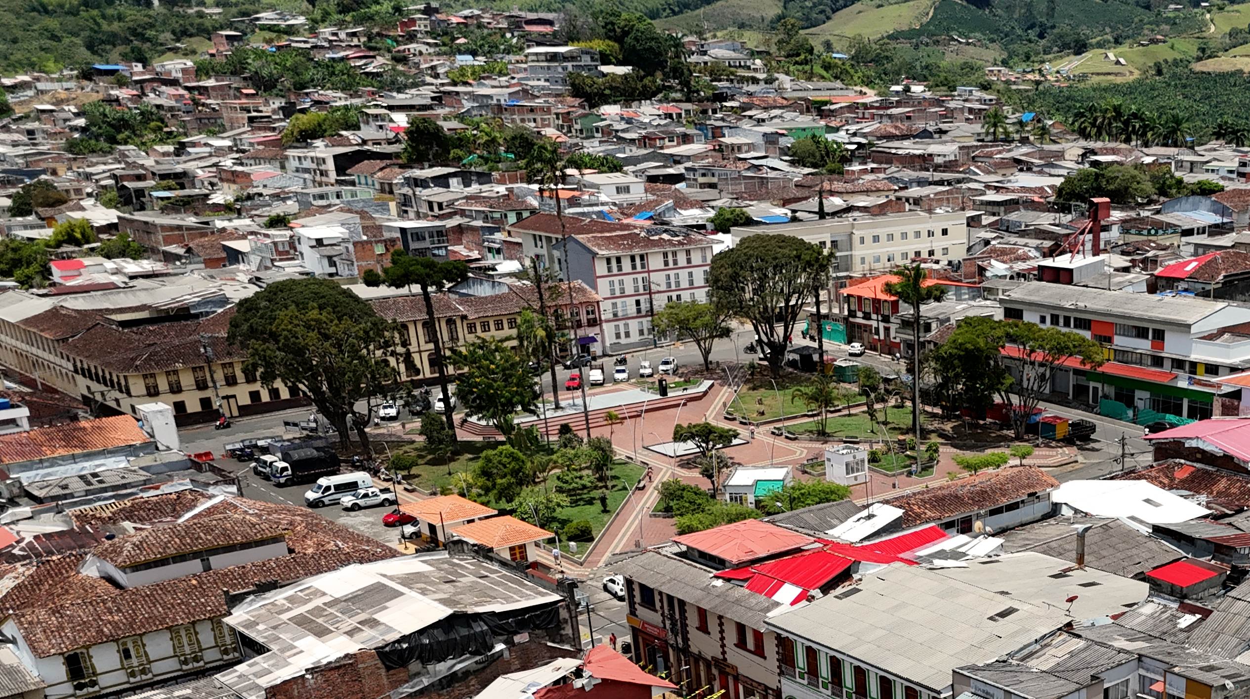 Vista aérea del Parque Uribe y el barrio, con la ladera de casas y las montañas cafeteras al fondo